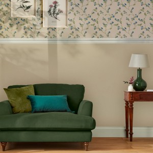 Beige Joules Vliestapete Uni (10m x 52cm) an Wand im Wohnzimmer mit Couch und Tisch.