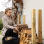 Frau stapelt Holz mit Relaxdays Holzstapelhilfe (4er Set) für Kaminholzregal.