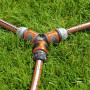 Gardena Y-Stück zur Schlauchabzweigung auf Rasen, orange/grau.