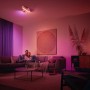 Philips Hue Centris Cross LED-Deckenleuchte mit 3 Spots in Weiß im Wohnzimmer mit farbiger Beleuchtung.