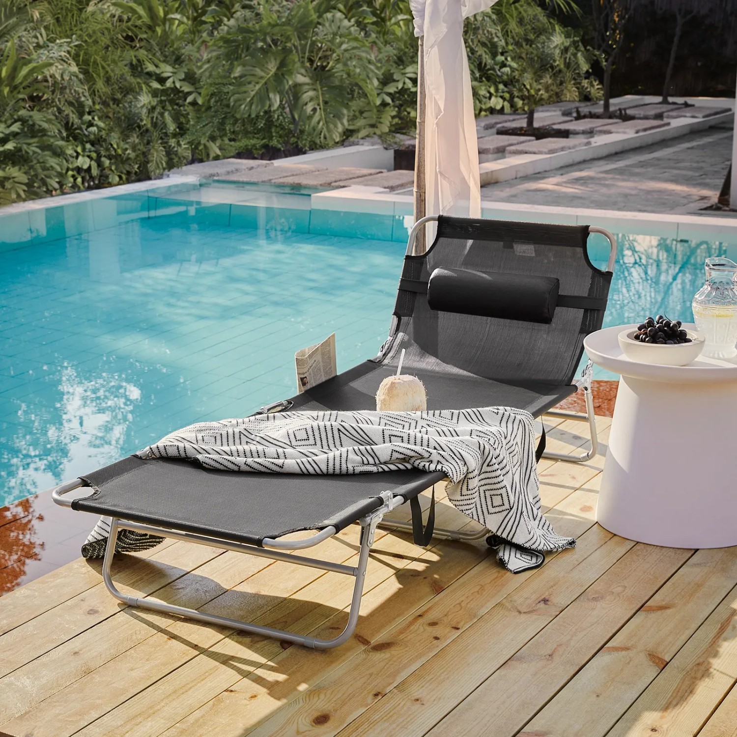 Schwarze, klappbare SoBuy Gartenliege OGS35-SCH mit Seitentasche und verstellbarer Rückenlehne am Pool.