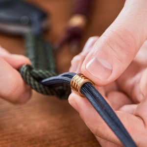 Detailaufnahme: Schwarzes Relaxdays Paracord Nylonseil (80m) wird von Händen bearbeitet.