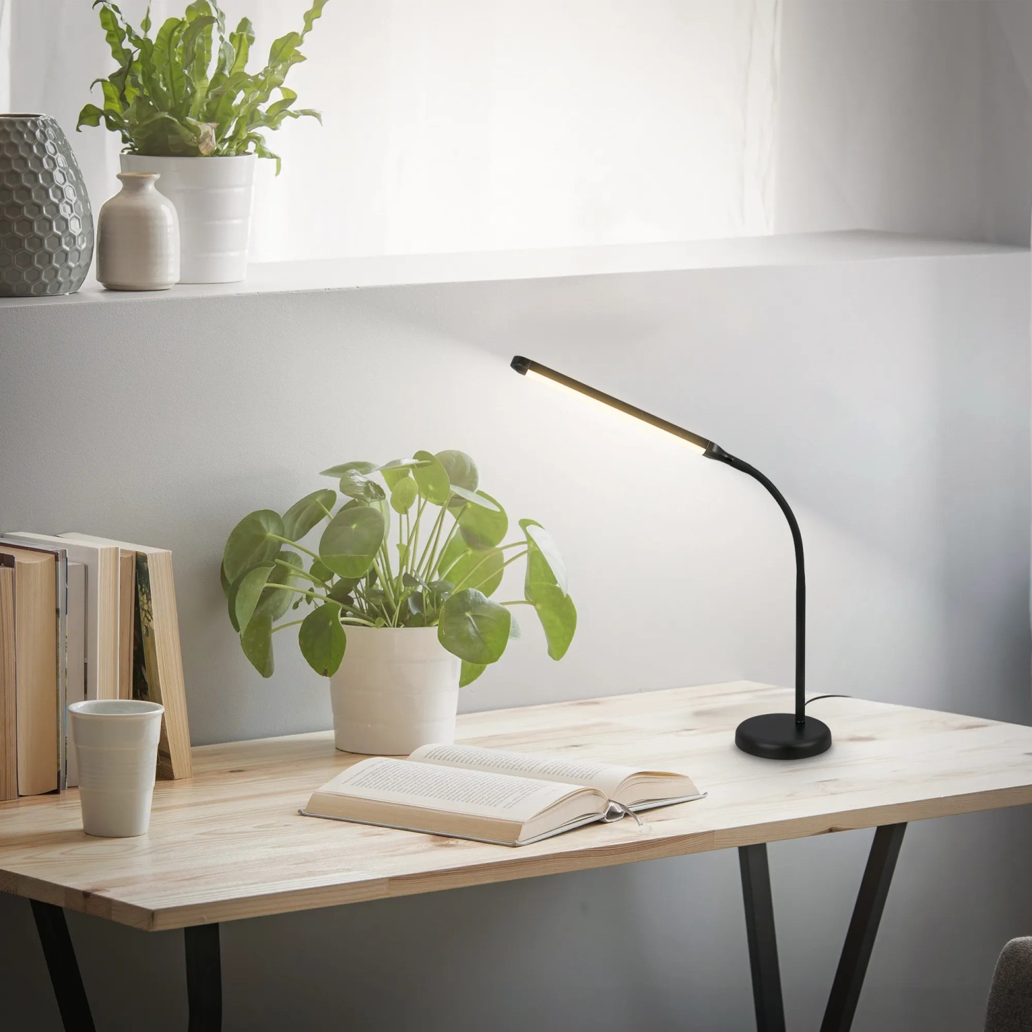 Schwarze Brilo LED-Tischleuchte Mura mit Touchdimmer und schwenkbarem Kopf auf einem Schreibtisch.