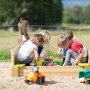 Wendi Toys Sandkasten mit Holzabdeckung, Sitzflächen und spielenden Kindern im Garten.
