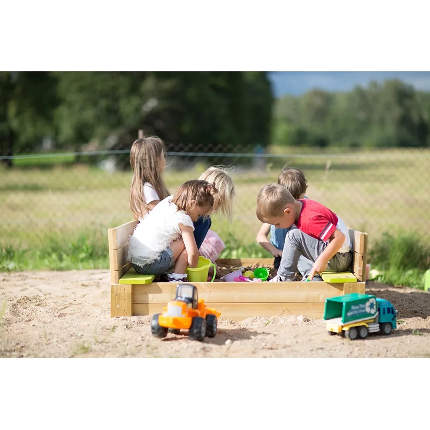 Wendi Toys Sandkasten mit Holzabdeckung, Sitzflächen und spielenden Kindern im Garten.