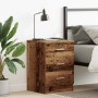 Nachttisch in Altholz-Optik aus Holzwerkstoff mit 3 Schubladen, neben Bett mit Lampe und Pflanze.