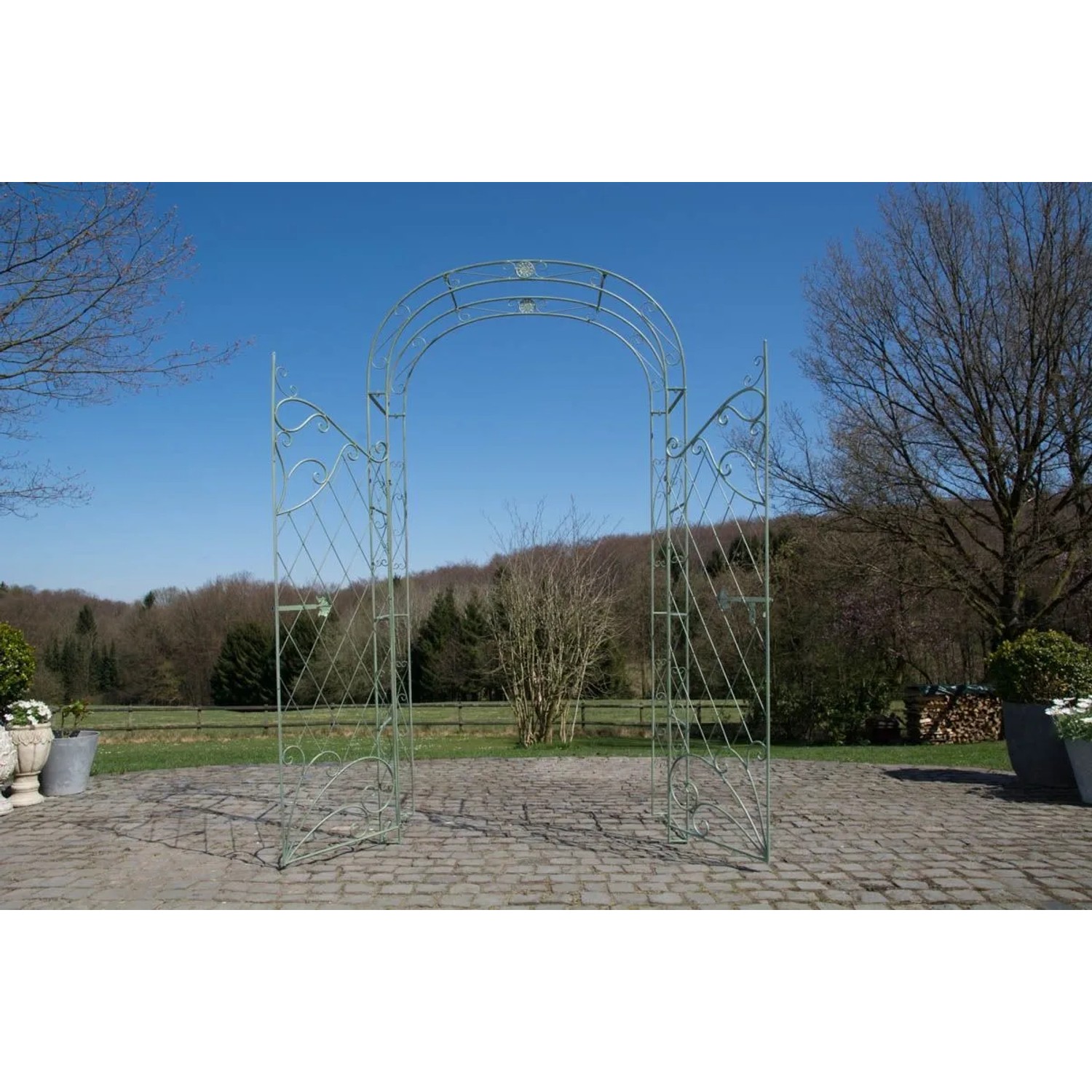 Antik-grüner Metall-Rosenbogen mit Tor als Rankhilfe im Garten. Dekorative Rankgitter für Kletterpflanzen.