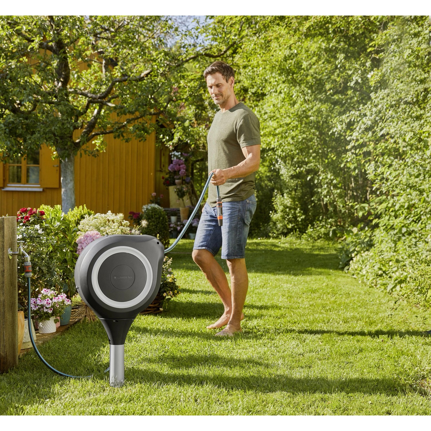 Gardena RollUp M Gartenschlauchbox mit Mann beim Bewässern im Garten.