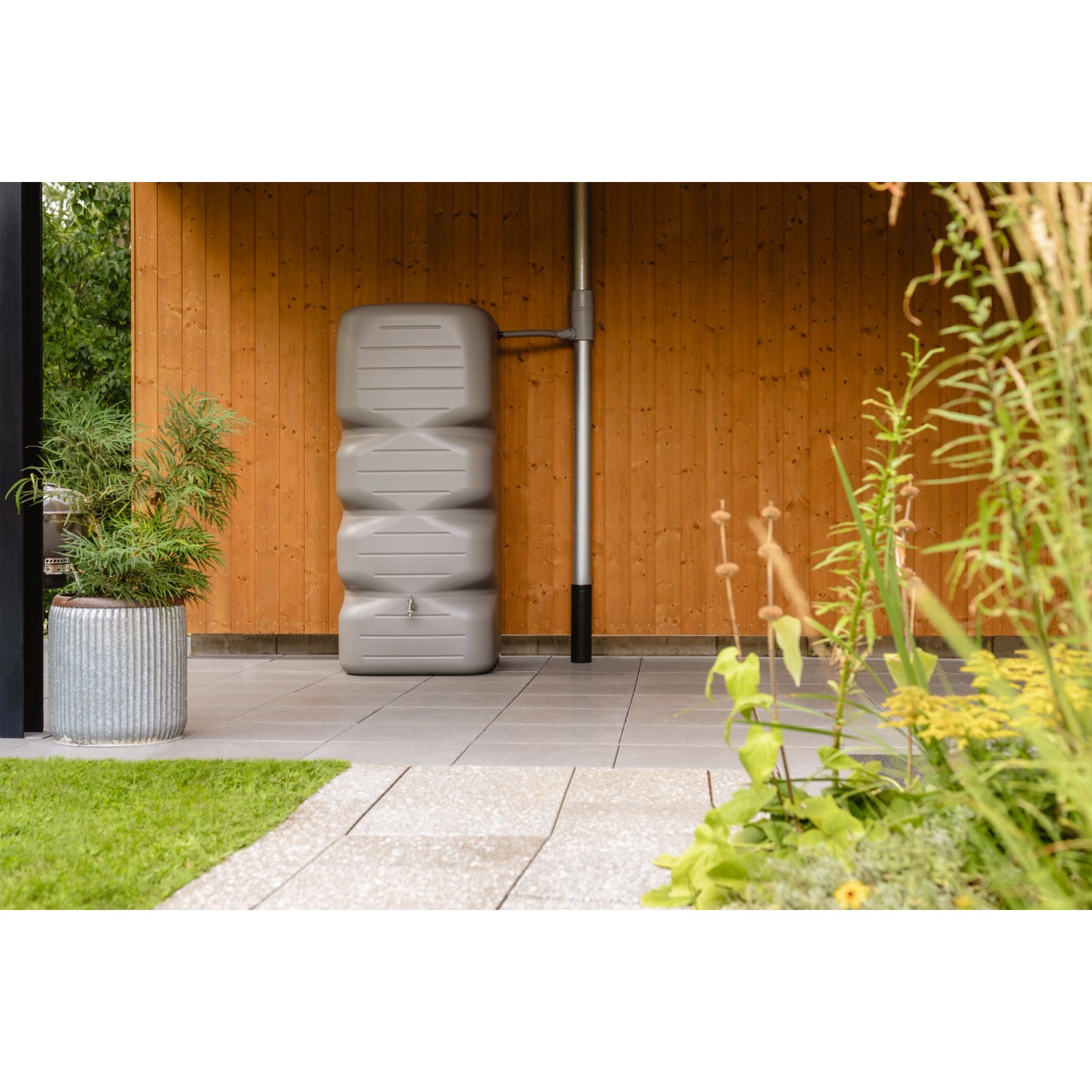 Garantia Gartentank Cubus 1000 l in Betongrau vor einer Holzwand. Regentonne für Garten.