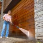 Frau reinigt Holzwand mit Kärcher Hochdruckreiniger K 7 Comfort Premium eco!Booster.