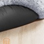 Graues, flauschiges Hundebett mit Anti-Rutsch-Noppen auf hellem Holzboden für sicheren Stand.