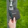 Gardena smart Water Control Bewässerungscomputer am Wasserhahn mit Hand, die den Knopf drückt.
