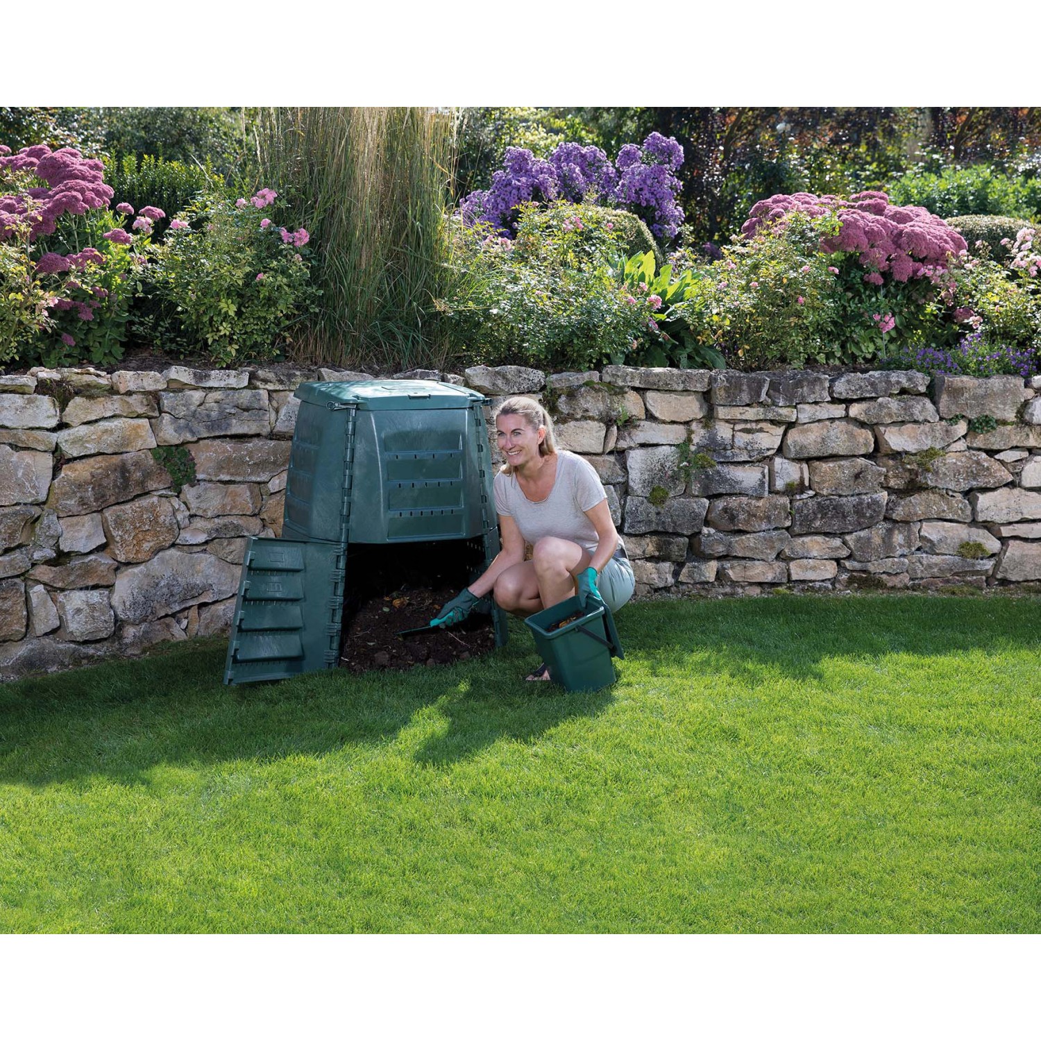 Garantia Thermostar Komposter 1000 l grün mit Frau bei der Kompostentnahme im Garten.
