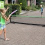 Schwarzes, verstellbares EXIT Sportnetz (155x300cm) beim Tennisspiel im Garten.