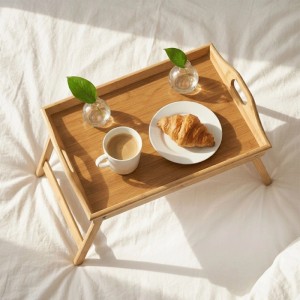 Klappbares Bambus Betttablett in Naturfarbe mit Kaffee und Croissant auf weißem Bett für entspanntes Frühstück.