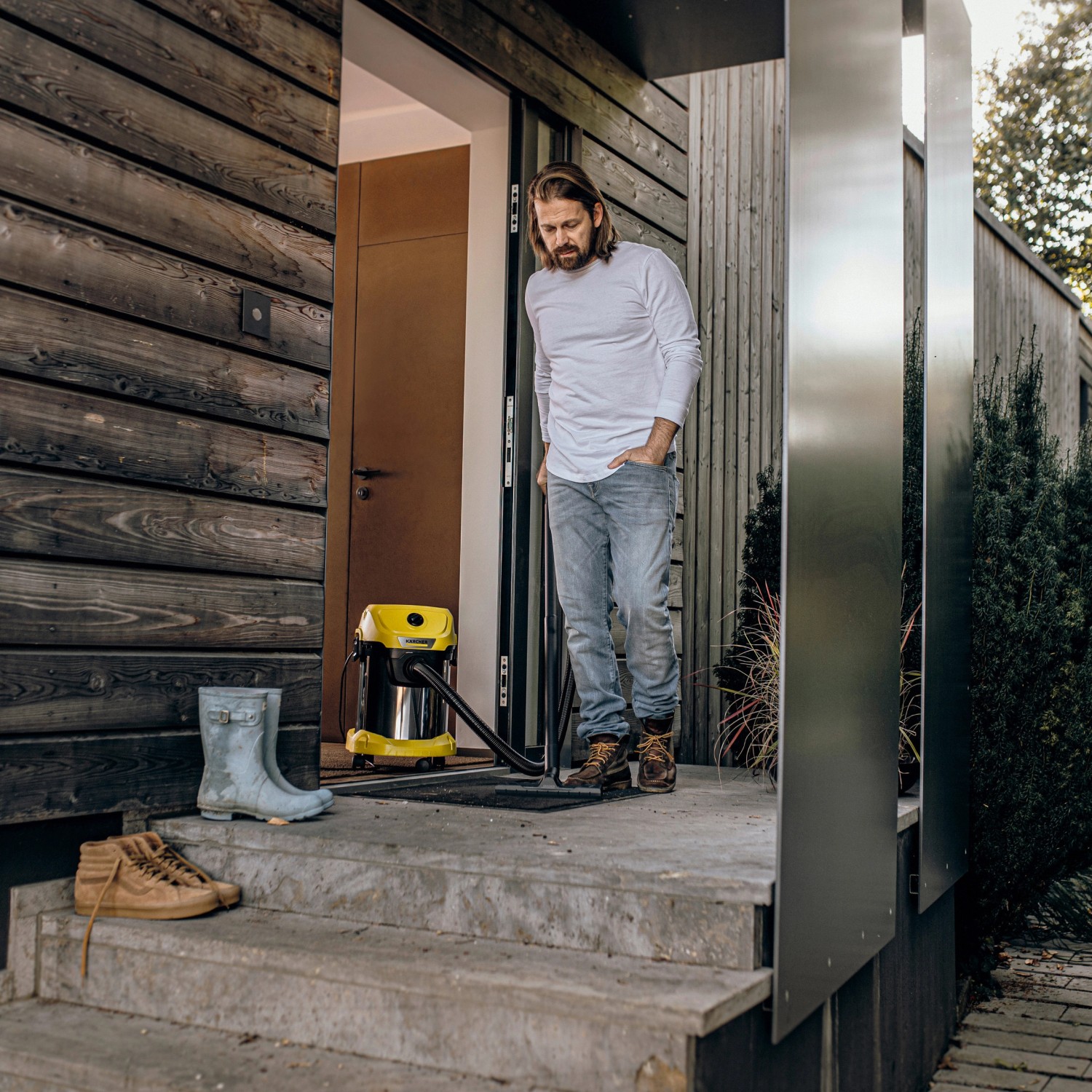 Kärcher WD 3 S V-17/4/20 Nass-/Trockensauger mit Edelstahlbehälter und Zubehör vor Haus.