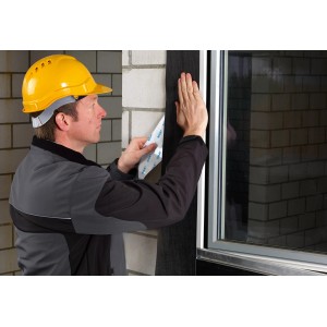 Handwerker verklebt schwarzes Siga Fentrim IS 2 Klebeband am Fensterrahmen.
