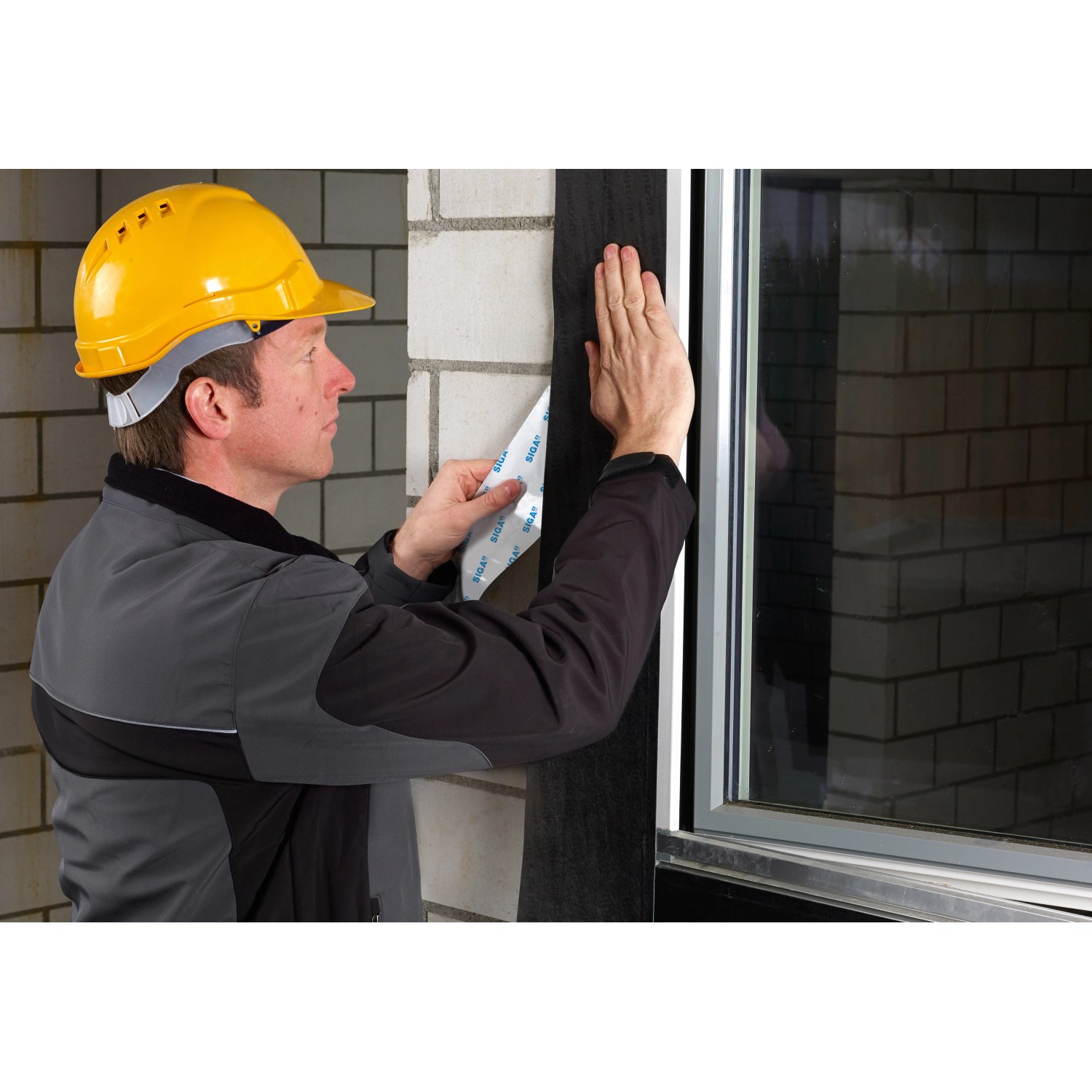 Handwerker verklebt schwarzes Siga Fentrim IS 2 Klebeband am Fensterrahmen.