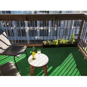 Grüner Primaflor Rasenteppich Park auf einem Balkon mit Tisch und Stühlen.