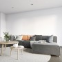 Wohnraum mit weiß gestrichener Wand mit Alpina Rollputz und grauer Couch mit Kissen.