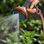 Gardena Premium Multibrause in Aktion: Hand hält Gartenspritze mit Wasserstrahl vor grünem Hintergrund.