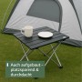 Kleiner, faltbarer Campingtisch aus dunklem Aluminium auf Gras, mit Tasse und Teller vor Zelt. Perfekt für Outdoor.