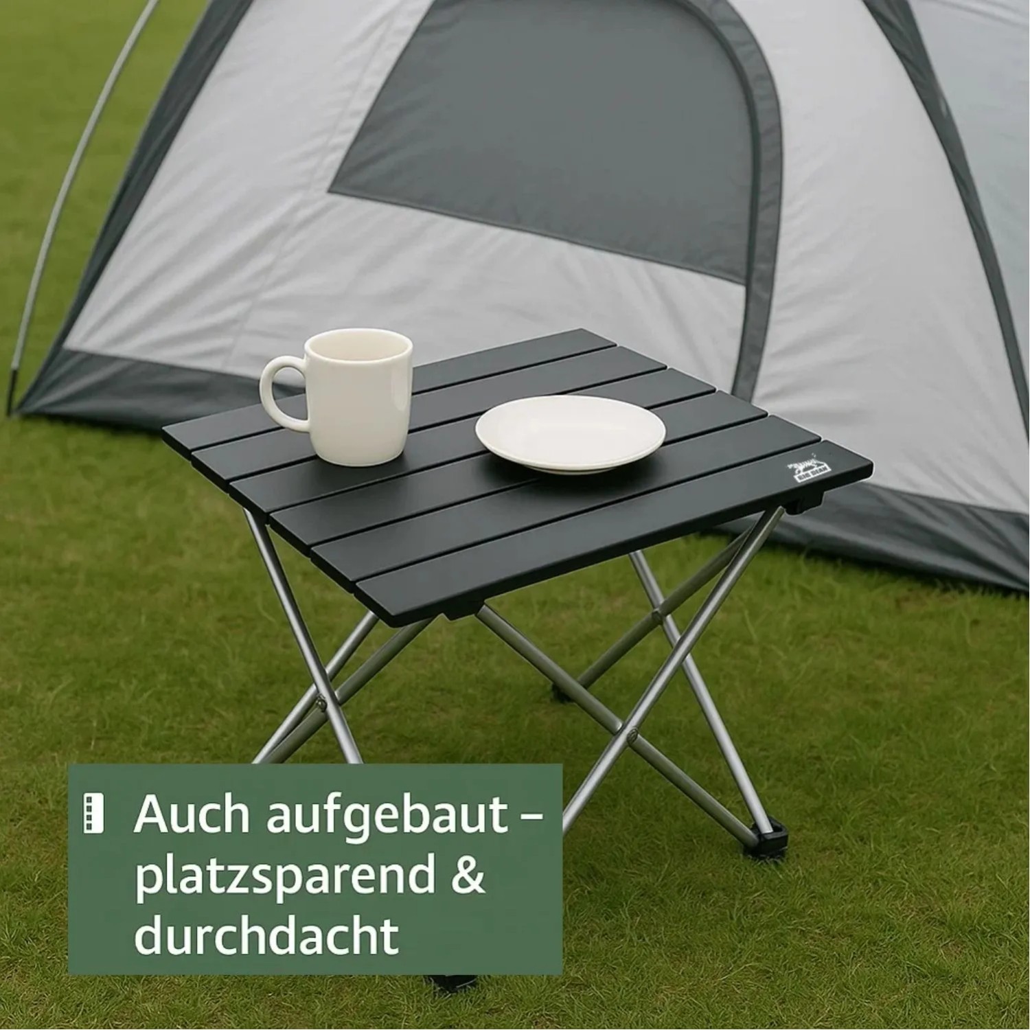 Kleiner, faltbarer Campingtisch aus dunklem Aluminium auf Gras, mit Tasse und Teller vor Zelt. Perfekt für Outdoor.