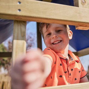 Lachender Junge im WICKEY Sandkasten King Kong aus Holz.