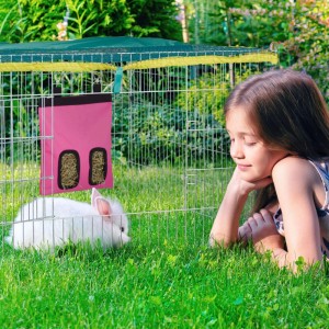 Pinke Heutasche mit Heu im Käfig, ein Kaninchen davor. Mädchen beobachtet. Futterspender für Kleintiere, aufhängbar.