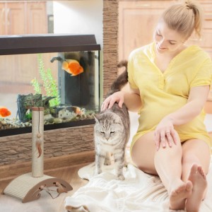 Beige-braune Relaxdays Kratzsäule mit Spielzeug und Kratzbrett neben einer Frau und einer Katze.