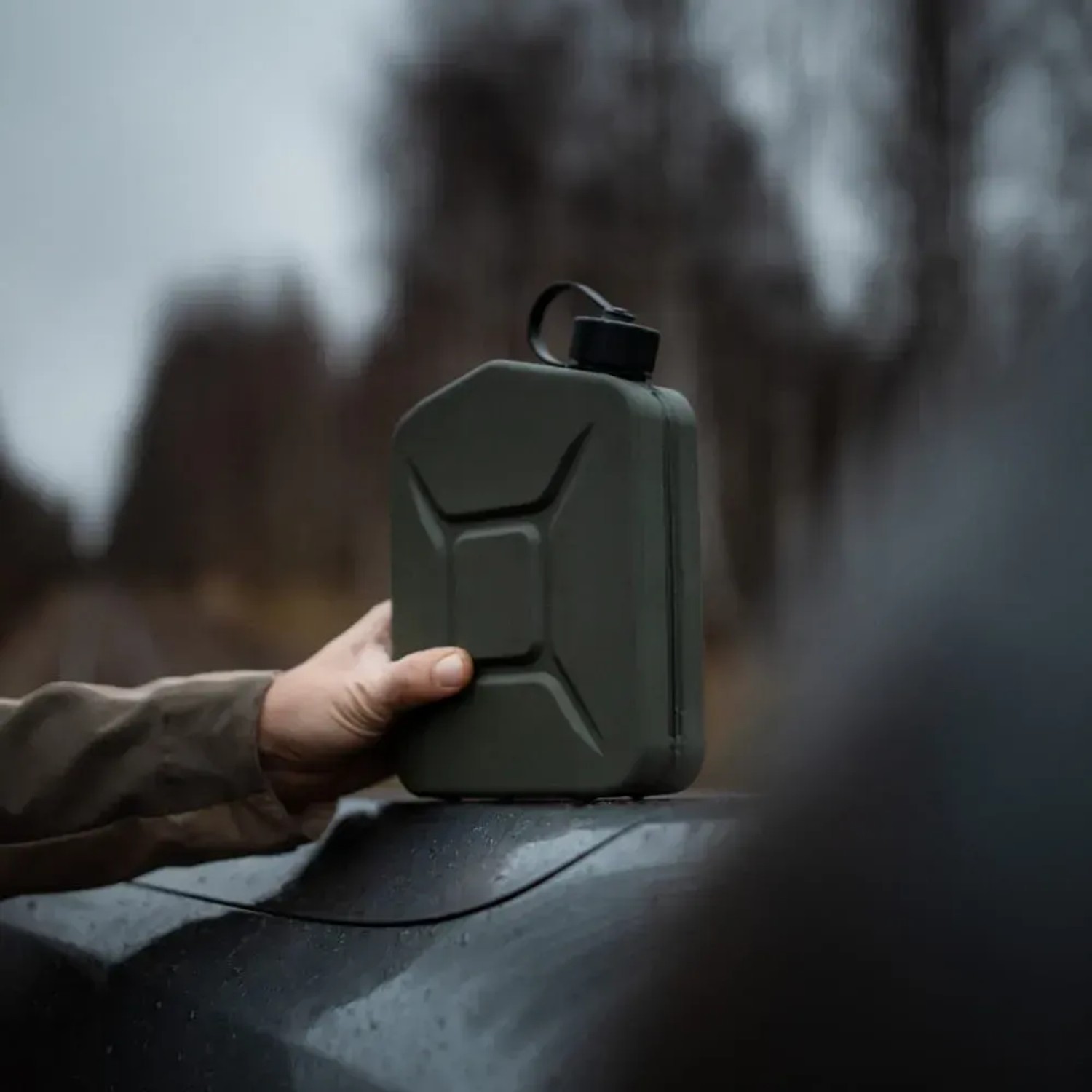 Olivgrüner 2L BW Proper Metall Kraftstoffkanister (Benzinkanister) in Hand auf Auto.