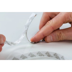 Paulmann MaxLED Strip: Hand zieht Schutzfolie von LED-Streifen ab. Selbstklebend, Tageslichtweiß.