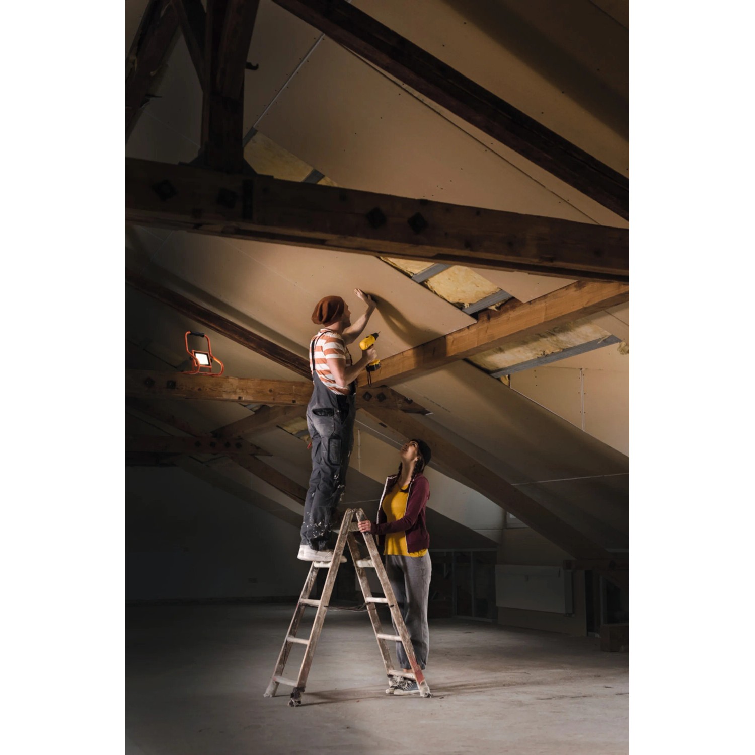 Zwei Personen renovieren einen Dachboden mit einem Ledvance LED-Arbeitslicht Worklight.