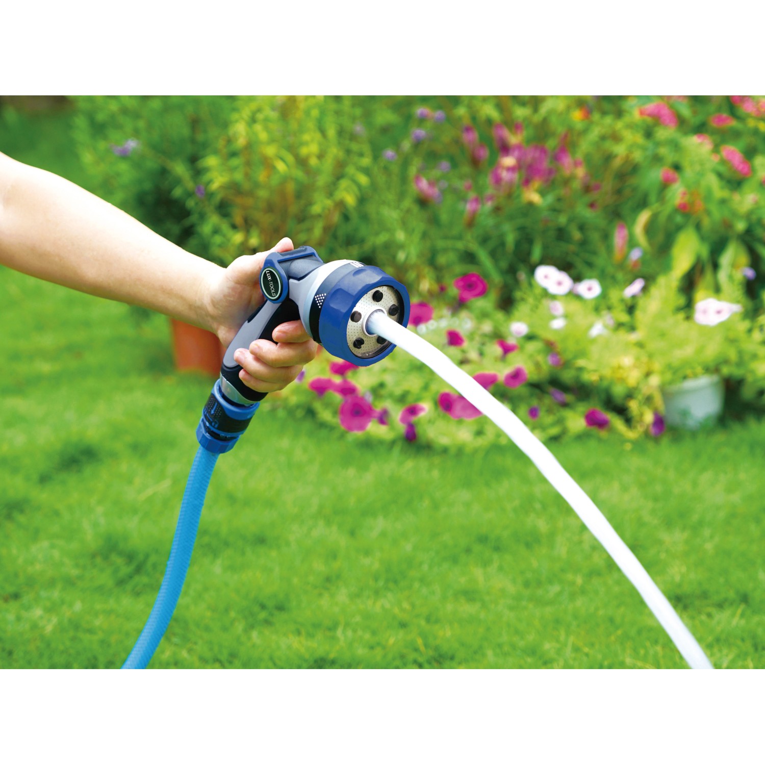 Hand hält Multifunktionsbrause mit 5 Strahlvarianten beim Bewässern des Gartens.