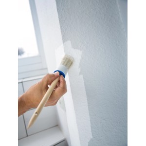 Hand streicht Wand mit LUX Ringpinsel Gr. 10. Der Pinsel hat helle Borsten und einen Holzgriff.