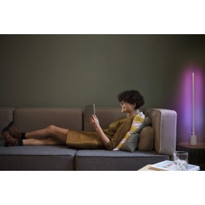 Frau entspannt mit Tablet neben Ledvance Smart+ WiFi Stehleuchte Slim (80cm) in Weiß.