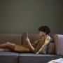 Frau entspannt mit Tablet neben Ledvance Smart+ WiFi Stehleuchte Slim (80cm) in Weiß.
