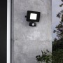 Schwarzer Eglo LED-Außenstrahler Faedo 3 an grauer Wand. Außenleuchte mit Bewegungsmelder.