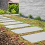 Diephaus Gehwegplatte Zementgrau 60x40 cm als Gartenweg mit Bewuchs.