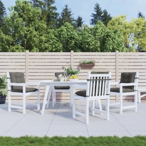 Vier dunkelgraue Niedriglehner-Auflagen auf weißen Gartenstühlen auf einer Terrasse. Bequeme Sitzkissen für Gartenmöbel.