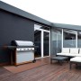 Wetterfester KARAT Outdoor Teppich Messina in Braun auf einer Terrasse mit Grill und Gartenmöbeln.