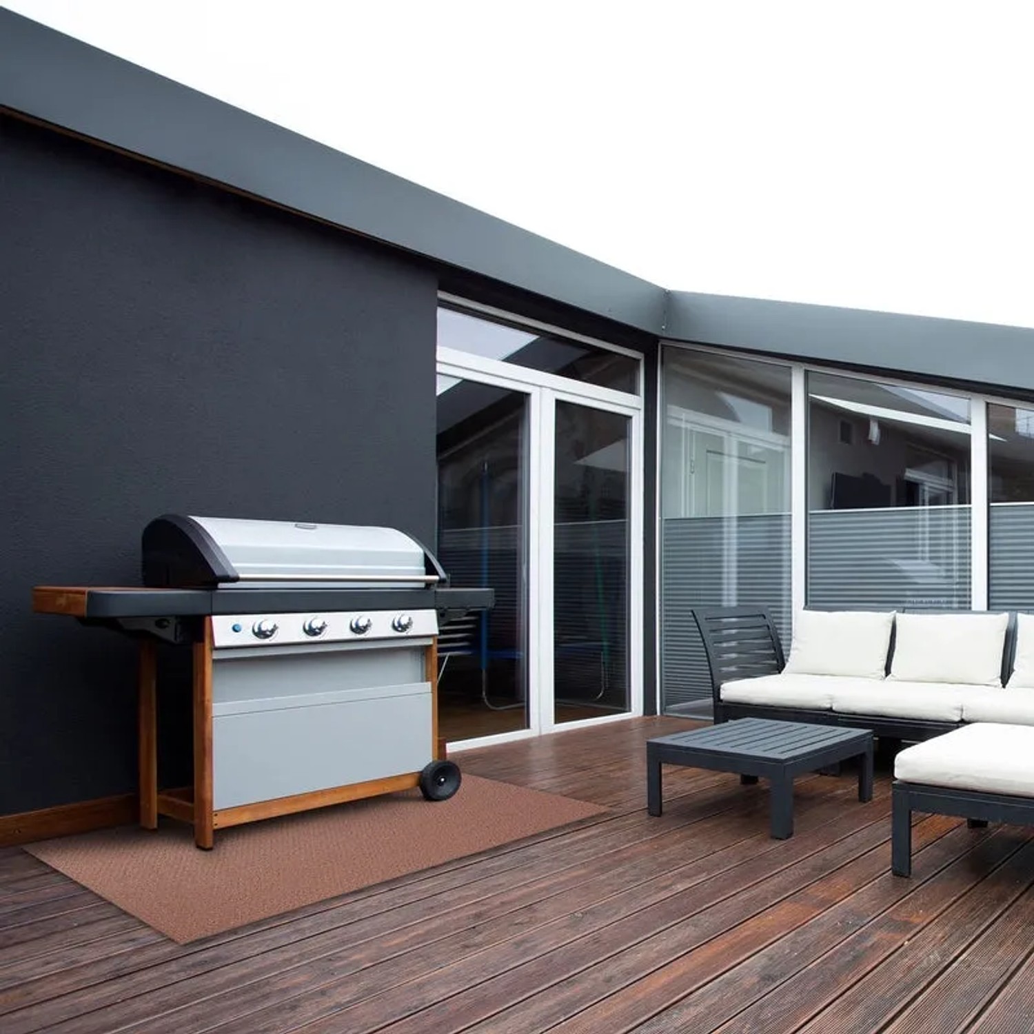 Wetterfester KARAT Outdoor Teppich Messina in Braun auf einer Terrasse mit Grill und Gartenmöbeln.