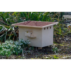 Großer, roter Hummelnistkasten aus Holz von Dobar im Garten mit Füllmaterial.