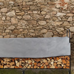 Schwarzes Relaxdays Kaminholzregal aus Stahl mit Holzstapel und grauer Abdeckung im Garten vor Steinwand.