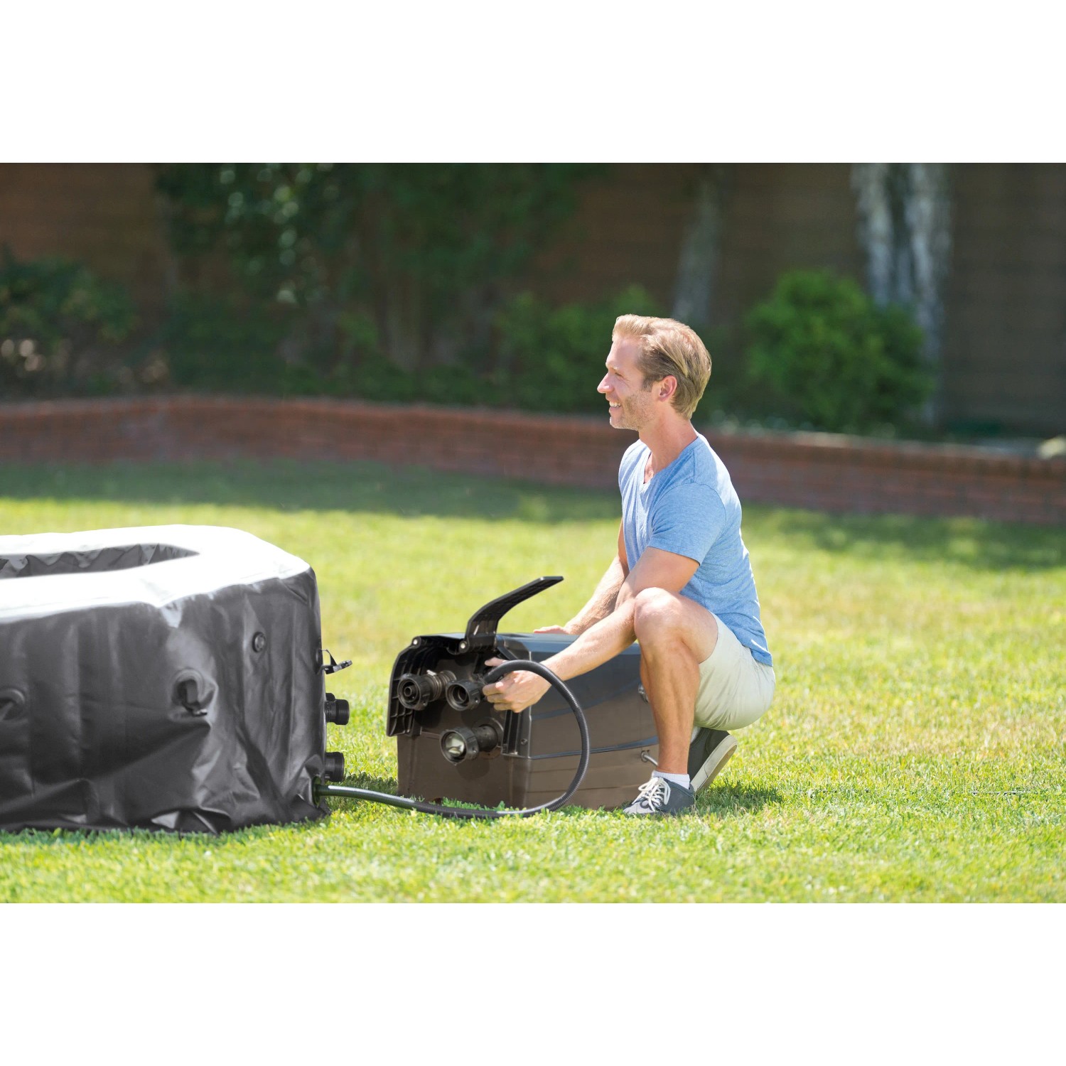 Schwarzer Intex PureSPA Bubble Jet Whirlpool (Ø 218cm) mit Bedienelement und Person im Garten.