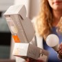Frau hält Osram Matter E27 LED-Lampe (9,5W) mit Verpackung. Dimmbare Glühbirnenform A75.
