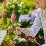 Frau bewässert Blumen mit Gardena Bewässerungsbrause AquaCount im Garten.