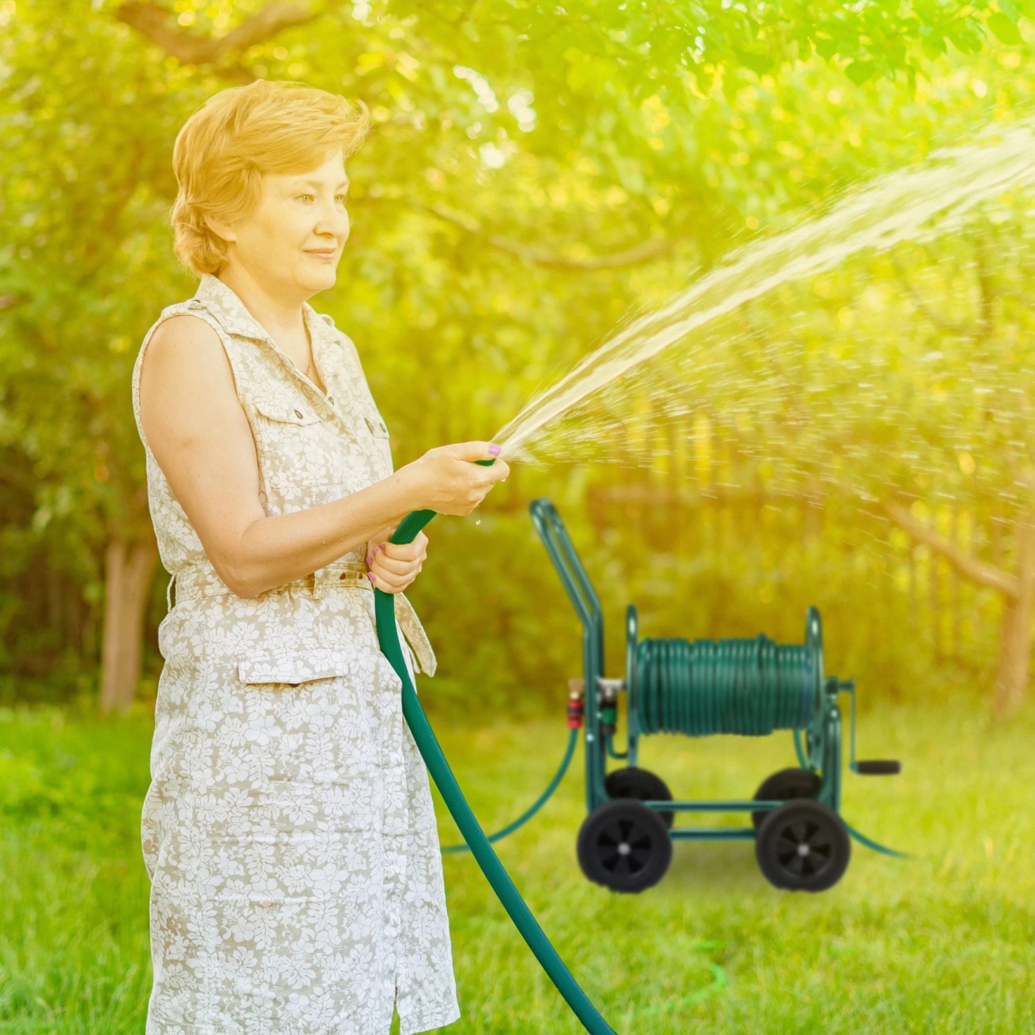 Frau gießt mit Gartenschlauch, aufgewickelt auf grünem Relaxdays Metall Schlauchwagen.