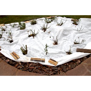 Weißes Aquagart Geotextilvlies 200g als Unkrautschutz im Garten über Pflanzen gelegt.