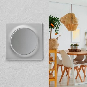 Grauer, runder Kreuzschalter Unterputz ohne Rahmen an weißer Wand. Modernes Lichtschalter Schalterprogramm.